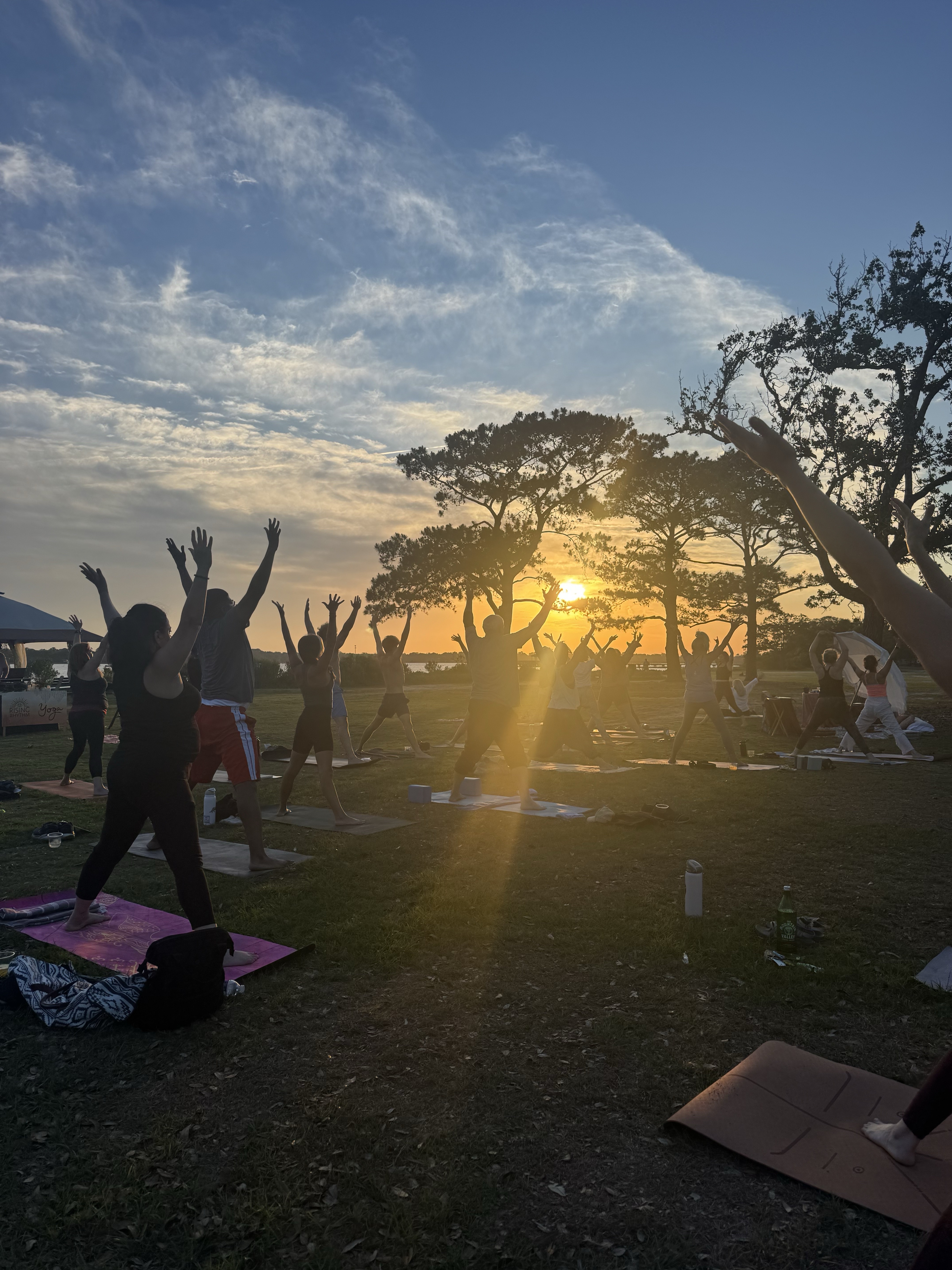 Community members doing yoga at sunset during the Rising Rhythm fundraiser at Brittlebank Park